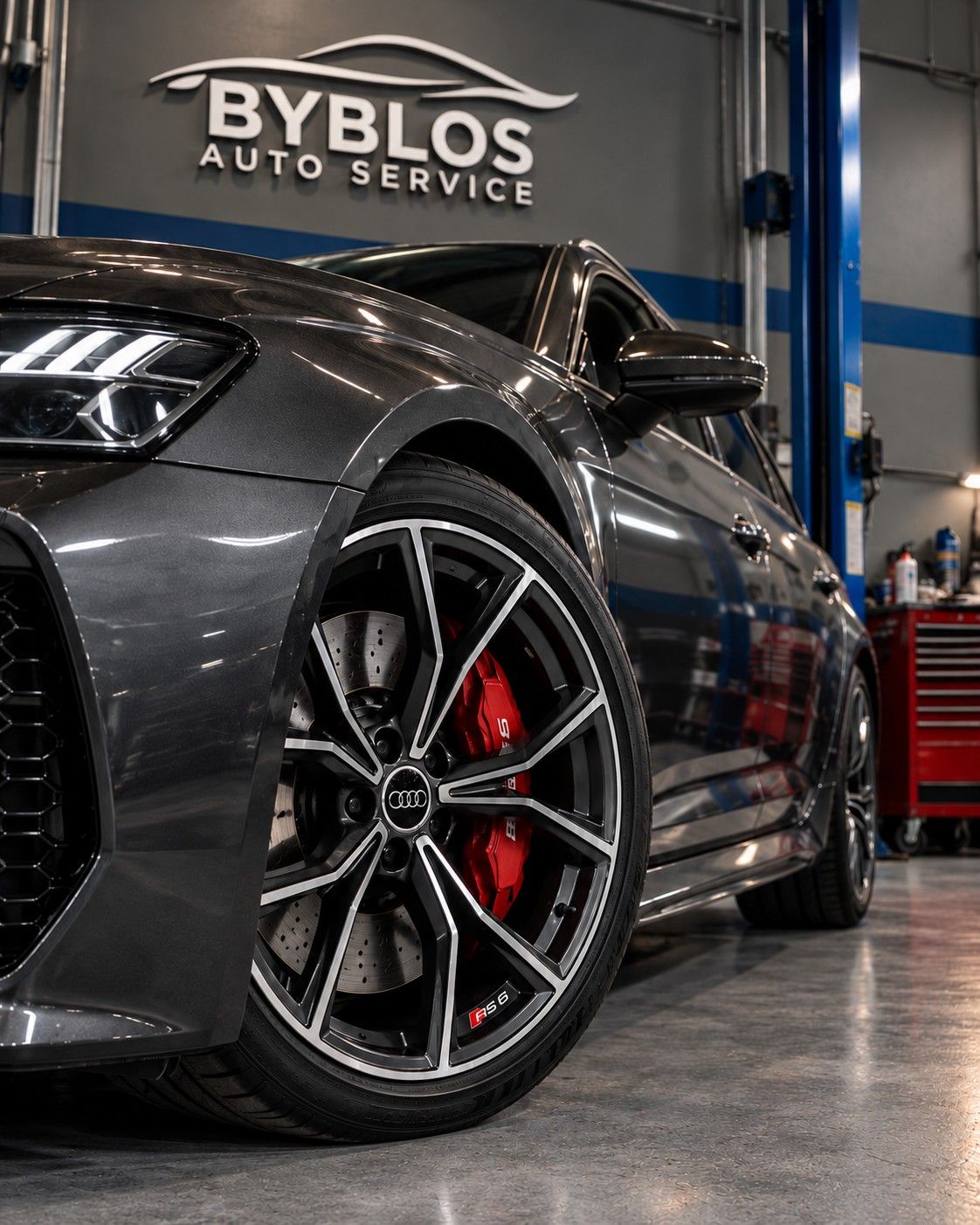 Close-up of an Audi RS 6 front wheel with a red brake caliper and drilled disc